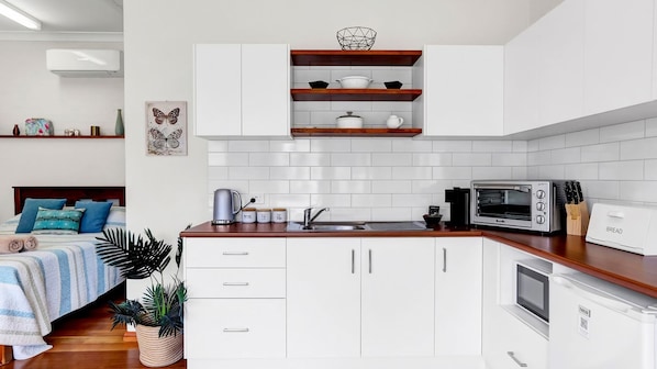 A modern kitchen with white cabinets, a wooden countertop, and a built-in oven.