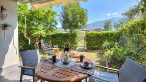 A patio with a table, chairs, a lantern, and a view of a garden and mountains. - The Peace Of The Lake - Private Garden, Near Beach (Arco)