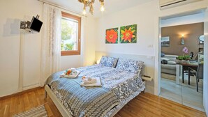 A bedroom with a bed, a mounted TV, a window with curtains, and two floral wall art pieces. - The Peace Of The Lake - Private Garden, Near Beach (Arco)