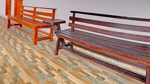 Deux bancs en bois adossés à un mur blanc, avec un sol à motifs.
