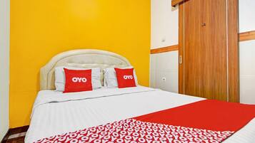 A bed with a white headboard, red and white pillows, and a red and white patterned blanket.
