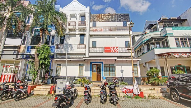 Un bâtiment avec une porte bleue, plusieurs motos garées devant et un drapeau sur le côté droit.