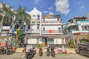 Un edificio con una puerta azul, varias motocicletas estacionadas adelante y una bandera a la derecha.