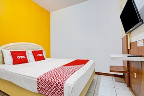 Habitación de hotel con cama, televisión montada en la pared y escritorio de madera.