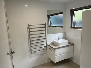 A modern bathroom with a white sink, a mirror above it, and a towel rack.