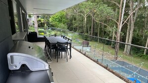A balcony with a table and chairs, overlooking a garden and trees. - Casa Lina w/ pool - the place to relax, unwind and reset (Catalina)