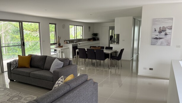 A modern living room with a grey sofa, dining area with chairs, and a kitchen with a stainless steel refrigerator. - Casa Lina w/ pool - the place to relax, unwind and reset (Catalina)
