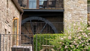 A stone building with a balcony and a water wheel. - A cottage that sleeps 8 guests  in 4 bedrooms (Castle Carrock)