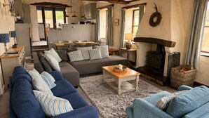 A cozy living room with a sofa, a coffee table, and a fireplace. - A cottage that sleeps 8 guests  in 4 bedrooms (Castle Carrock)