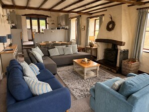 A cozy living room with a sofa, a coffee table, and a fireplace. - A cottage that sleeps 8 guests  in 4 bedrooms (Castle Carrock)