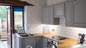 A kitchen with grey cabinets, a wooden countertop, a built-in oven, and a window with a view of greenery. - A cottage that sleeps 8 guests  in 4 bedrooms (Castle Carrock)
