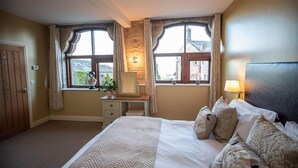 A bedroom with a bed, a dresser, a window with curtains, and a lamp. - A cottage that sleeps 6 guests  in 3 bedrooms (Castle Carrock)