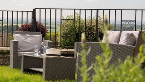A wicker outdoor seating area with a view of the countryside. - Luxury cottage with enclosed garden and 2 dogs welcome (Castle Carrock)