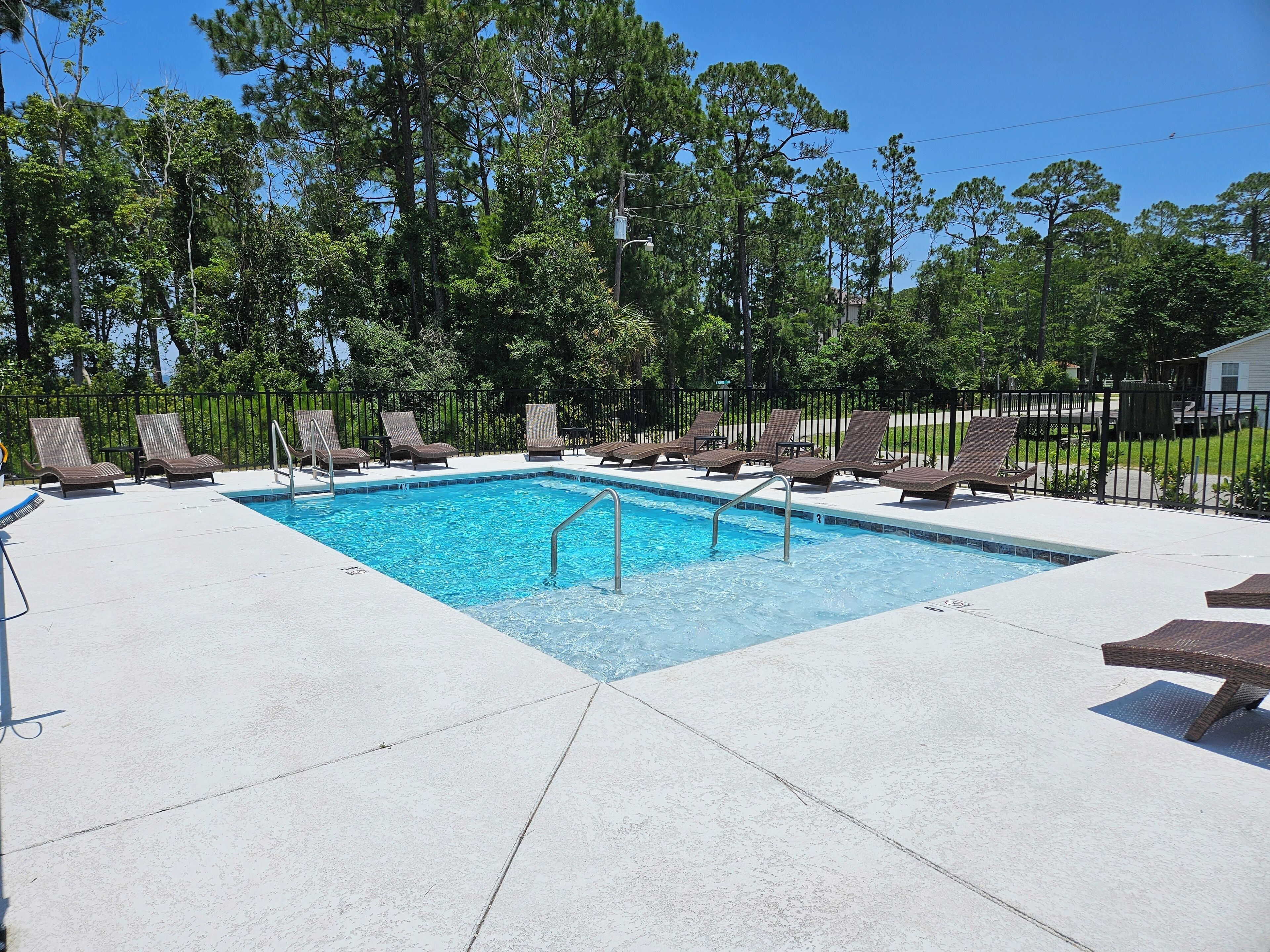 A rectangular pool with a metal ladder, surrounded by a white deck.