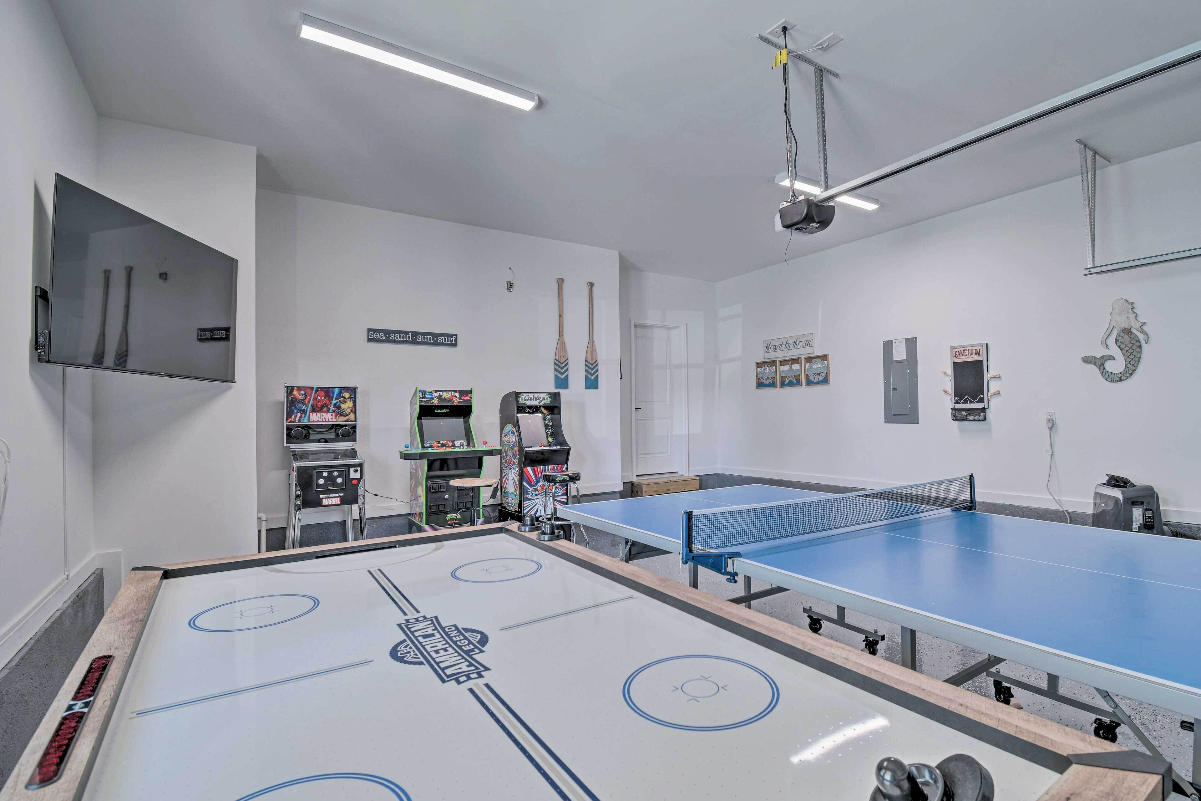 A room with a ping pong table, arcade games, and a sign indicating a game room.