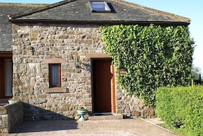 Traditional cottage with a pitched roof and small dormer window, featuring a wooden door and window with a shutter.