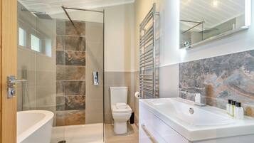 A modern bathroom with a glass-enclosed shower, a white toilet, and a large white sink with a mirror above it.