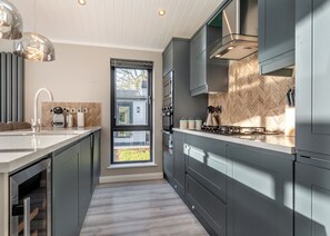 A modern kitchen with a large window, stainless steel appliances, and a herringbone tile backsplash.