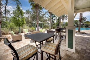 An outdoor patio with wicker furniture, a table, and chairs. - 5 Minute Walk to Pool! 6-Seater Cart & 8 Bikes! Sleeps 15! - Just Beachy at NatureWalk on 30A (Santa Rosa Beach)