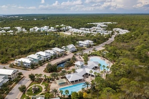Un resort con varias edificaciones, una piscina central y abundante vegetación.