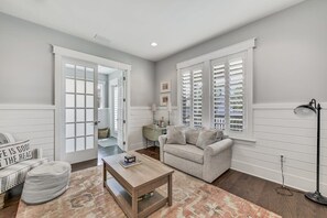 A living room with a sofa, coffee table, and a lamp. There is a door leading to another room. - 5 Minute Walk to Pool! 6-Seater Cart & 8 Bikes! Sleeps 15! - Just Beachy at NatureWalk on 30A (Santa Rosa Beach)