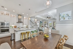 A spacious kitchen with white cabinetry, a central island, and bar stools.