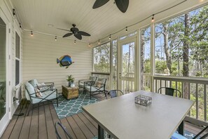 A covered porch with a table and chairs, a ceiling fan, and a fish decoration.