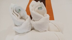 A pair of neatly folded white towels with a tag on them, placed on a wooden surface. - Vlodge House (Chiang Mai)