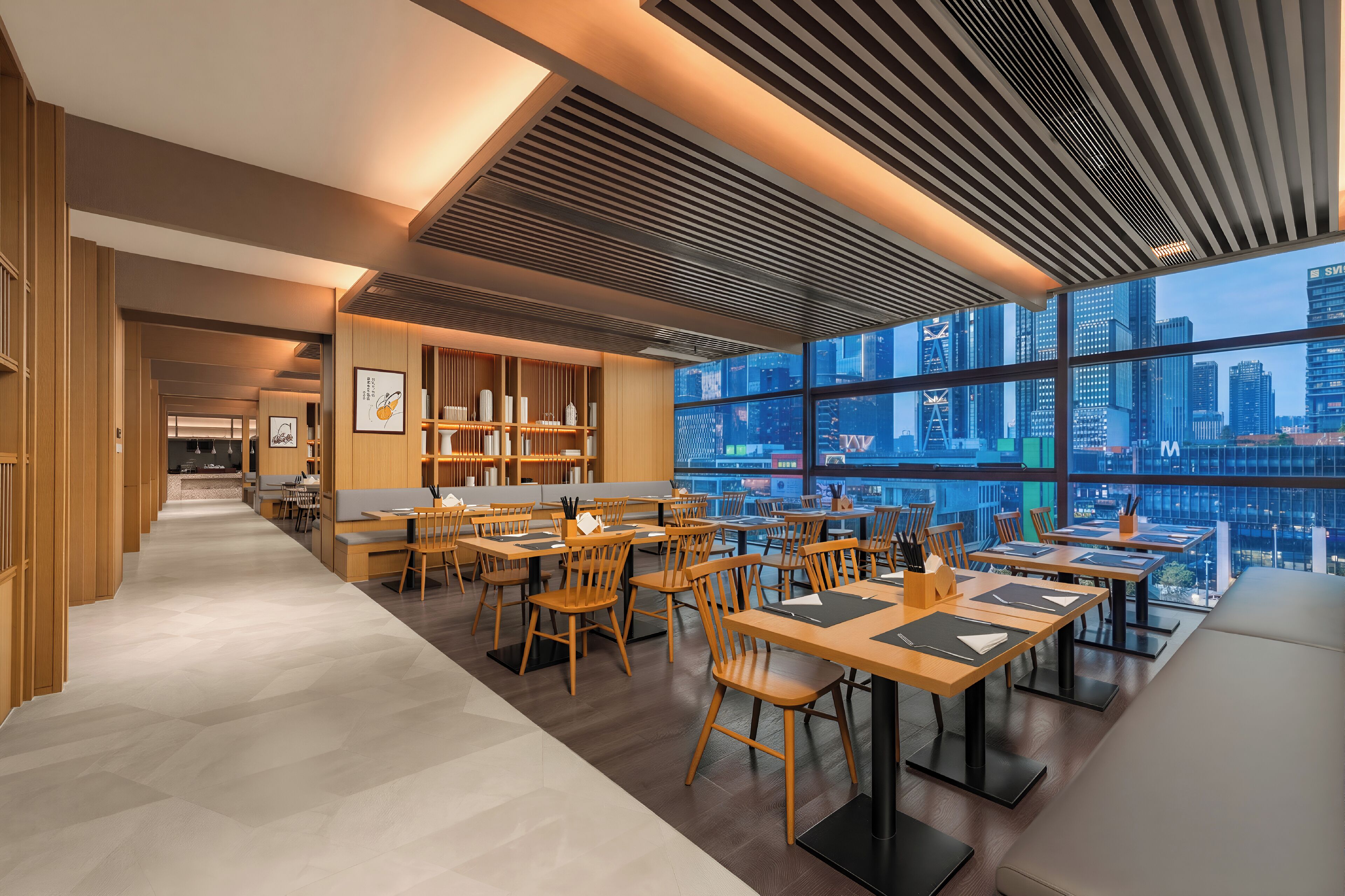 Un comedor moderno con muebles de madera y ventanas amplias que ofrecen vistas a la ciudad.