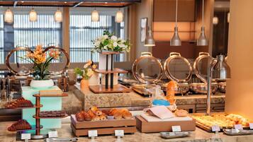 A buffet with various food items and a floral centerpiece.