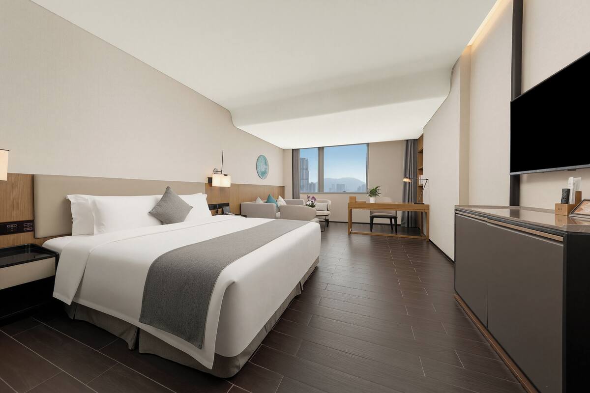 Une chambre d’hôtel moderne, dotée d’un grand lit, d’un bureau et d’une télévision.
