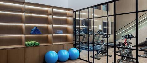 A gym with exercise equipment, a wooden wall with shelves, and a staircase.