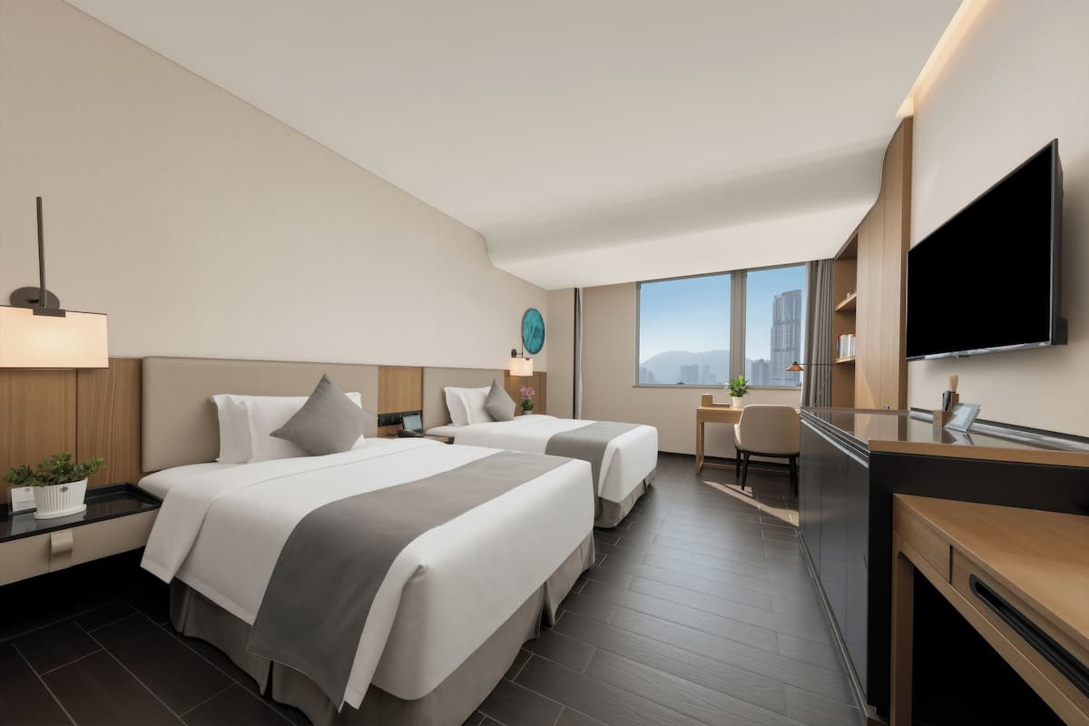 Une chambre d’hôtel avec deux lits, un bureau, une télévision et une vue sur la ville.