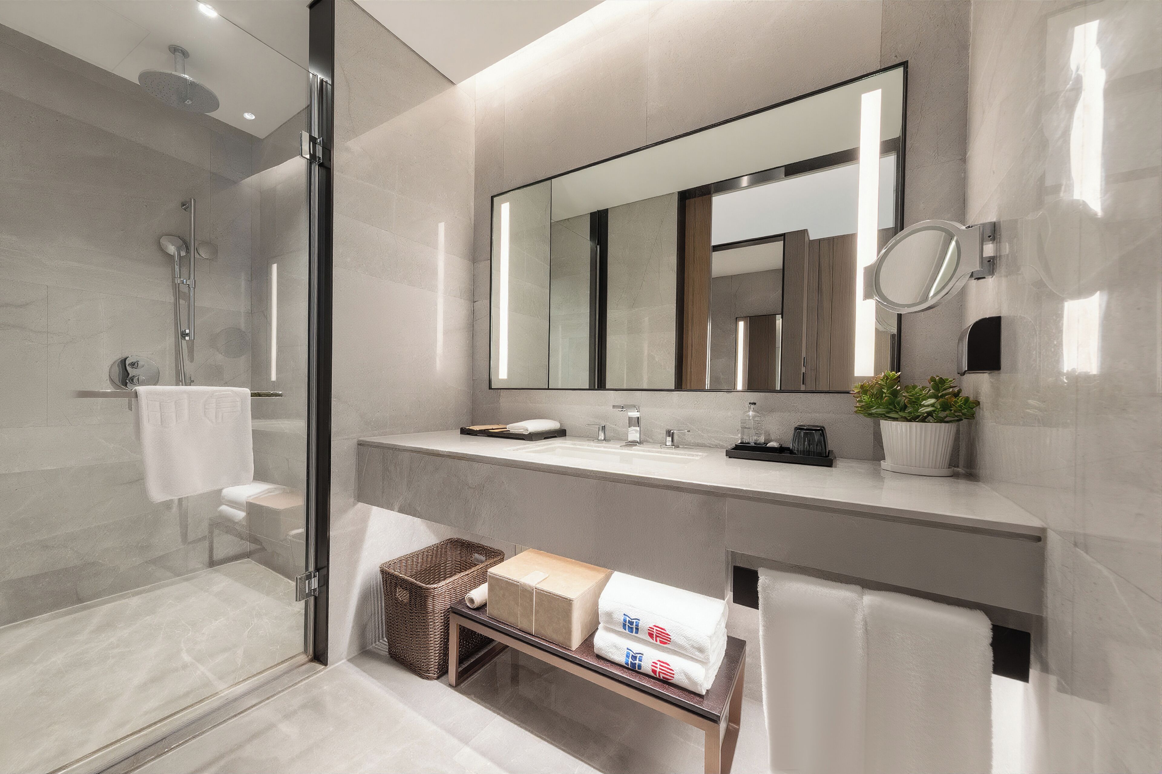 A modern bathroom with a glass shower enclosure, a large mirror, and a vanity with a sink and countertop.