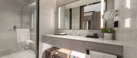 A modern bathroom with a glass shower enclosure, a large mirror, and a vanity with a sink and countertop.