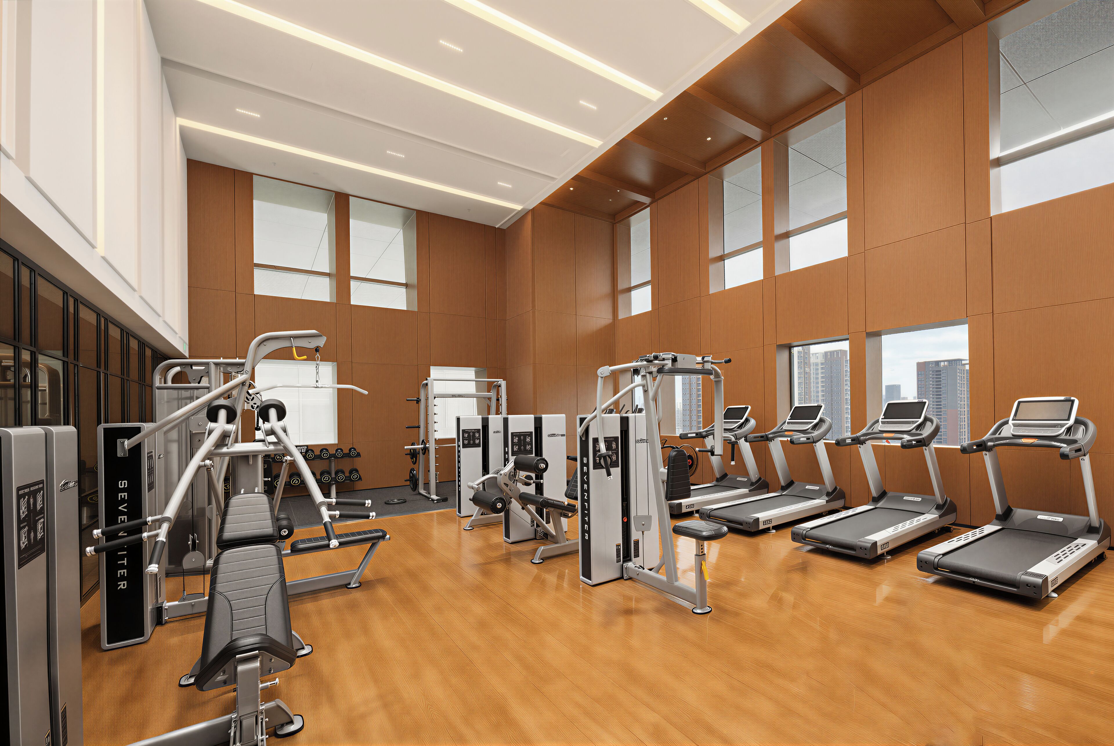Un gimnasio amplio con cintas de correr, máquinas de pesas y un espejo grande.