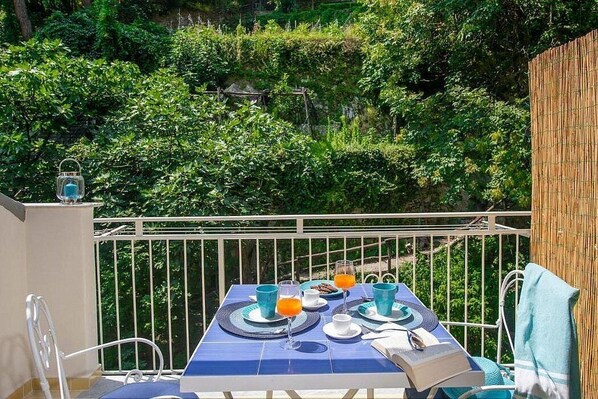 A balcony with a table set for breakfast, surrounded by lush greenery.