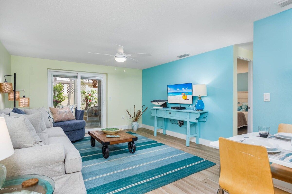 A living room with a sofa, a coffee table, a dining table with chairs, and a blue wall.