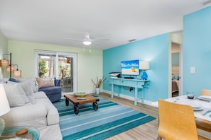 A living room with a sofa, a coffee table, a dining table with chairs, and a blue wall. - Lounge at Lulu's #2 | 5 Min to Beach | Pool | Dog (Sarasota)