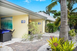 A hotel with a covered outdoor seating area, a small garden with palm trees, and a sign indicating a pool and restaurant. - Lounge at Lulu's #2 | 5 Min to Beach | Pool | Dog (Sarasota)