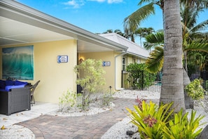A hotel with a covered outdoor seating area, a small garden with palm trees, and a sign indicating a pool and restaurant. - Relax at Lulu's! Pool, Walk to Beach, Dog friendly (Sarasota)