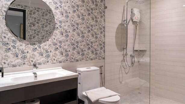 A modern bathroom with a round mirror, a toilet, a shower, and a sink.