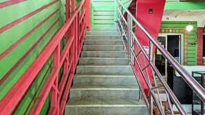 A staircase with red railings and green walls, leading to an upper level. - Hotel O Surya HotelNearTaman Anggrek Pkk Watansoppeng (Watansoppeng)