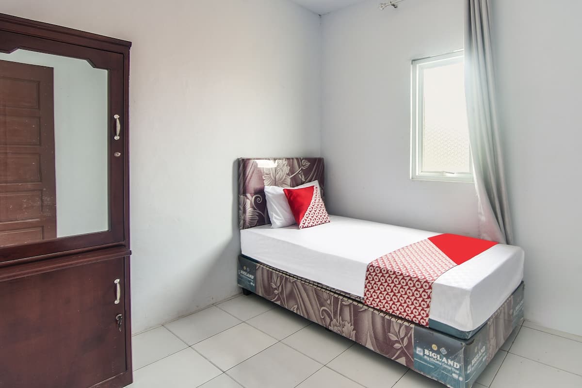 A small bedroom with a bed, a wardrobe, and a window.