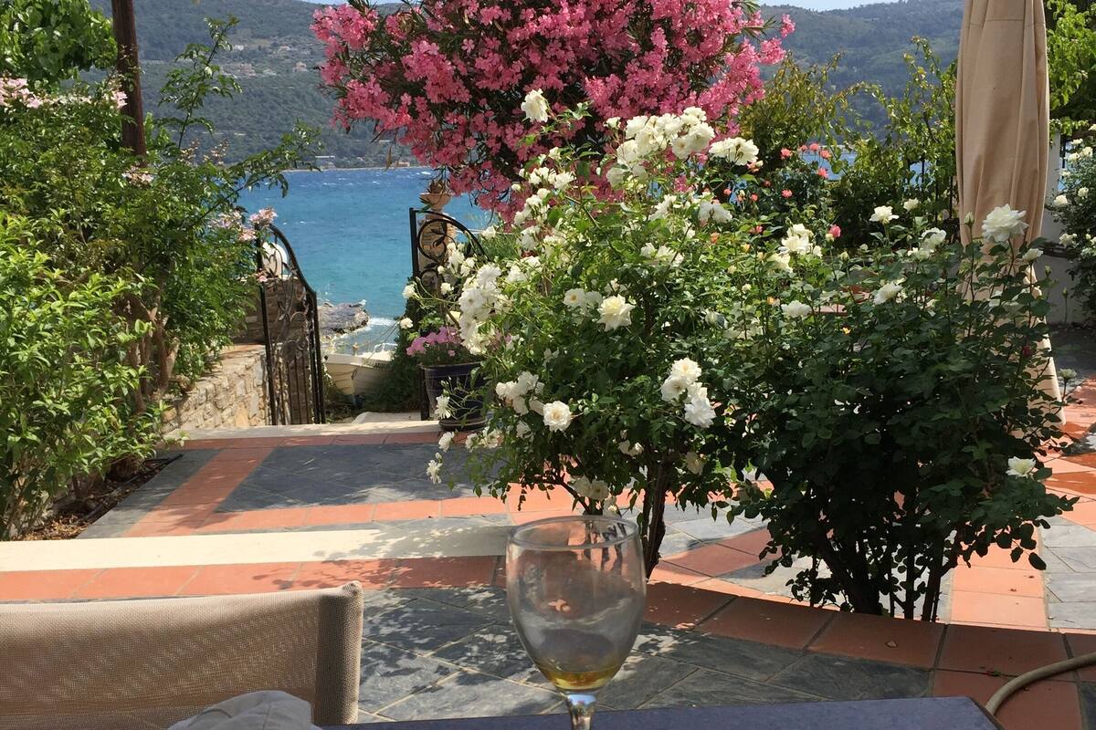 A table with a glass of white wine, a woven placemat, and a beige cloth.