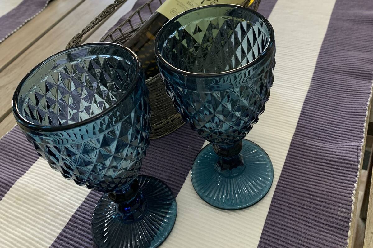 A table with a bottle of wine, two glasses, and a woven basket.