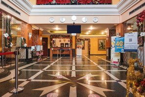 Hotellin aula, jossa on sisäänkirjautumistiski, tähtikuvioilla koristeltu lattia ja joulukoristeita.