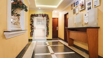 Un vestíbulo de hotel con una recepción, una estatua decorativa, un adorno navideño y un suelo de baldosas.