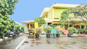 Un edificio con fachada verde y amarilla, un letrero que indica una clínica médica y una calle mojada que sugiere lluvia reciente.