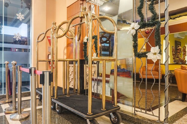 A golden trolley with a black platform, surrounded by metal barriers and a glass window reflecting interior decor. - Palette Ancol Near Dufan Formerly BI Executive (Jakarta)